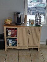 A kitchenette with a coffee maker, a basket of snacks, and a coffee machine.