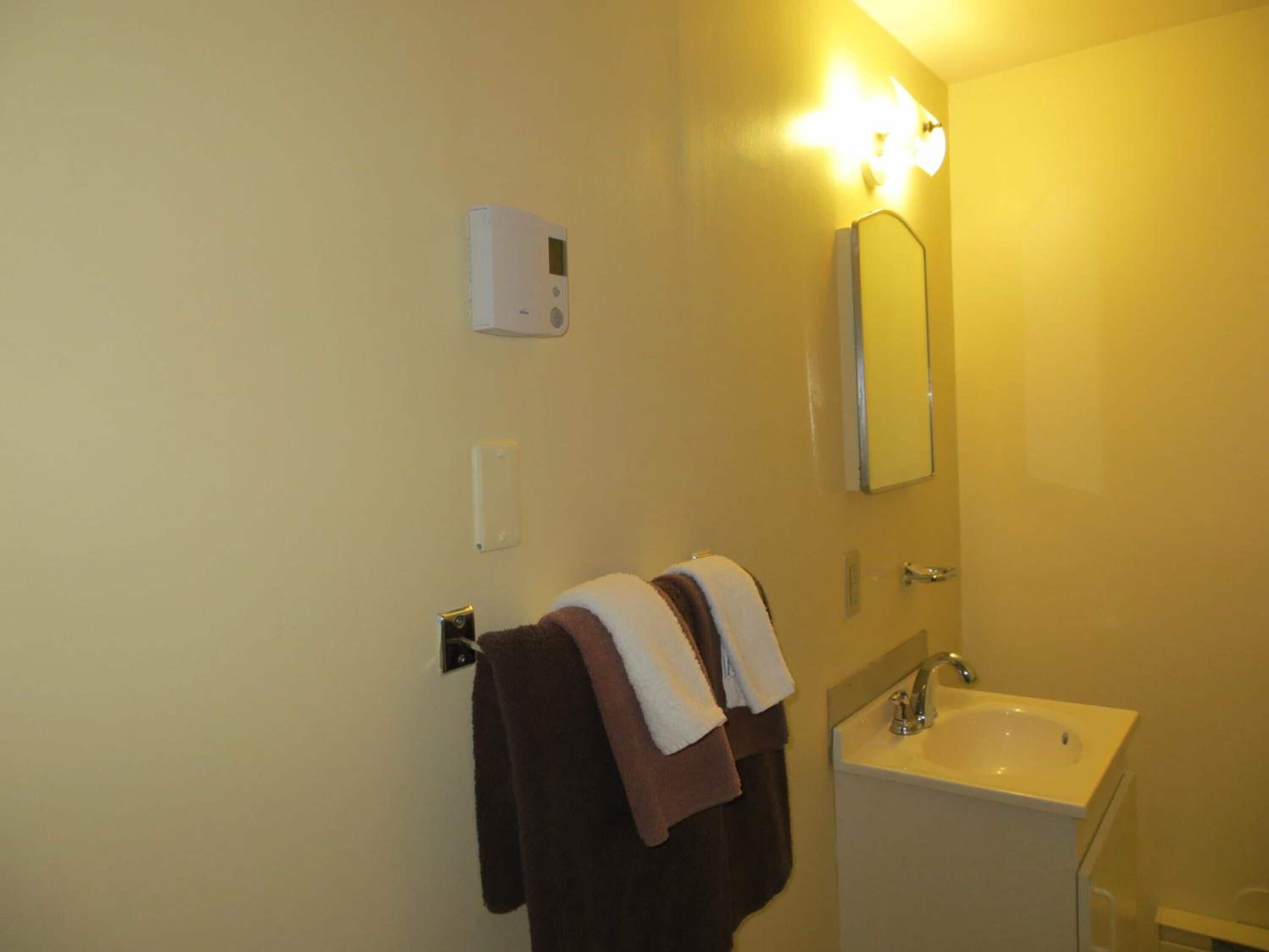 Une salle de bain avec un lavabo blanc, un miroir et un porte-serviettes avec deux serviettes.