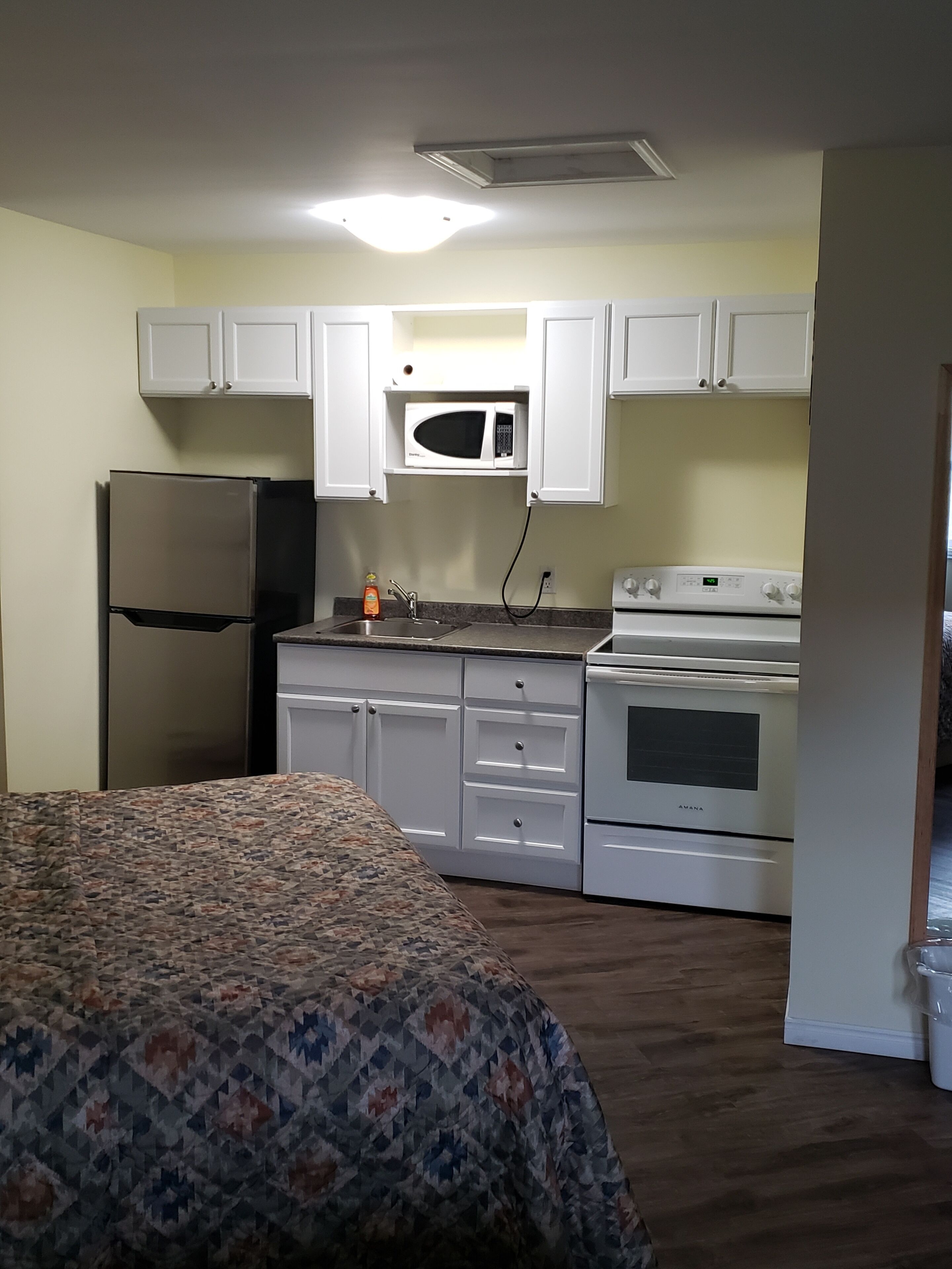 A compact kitchen with white cabinets, a microwave, a refrigerator, and an oven.