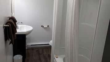 A bathroom with a sink, mirror, and shower.