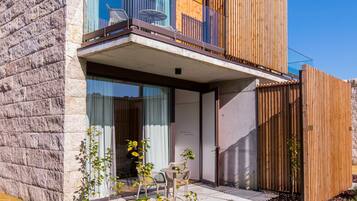 Una casa moderna de dos pisos con fachada de piedra, amplios ventanales de vidrio y una valla de madera.
