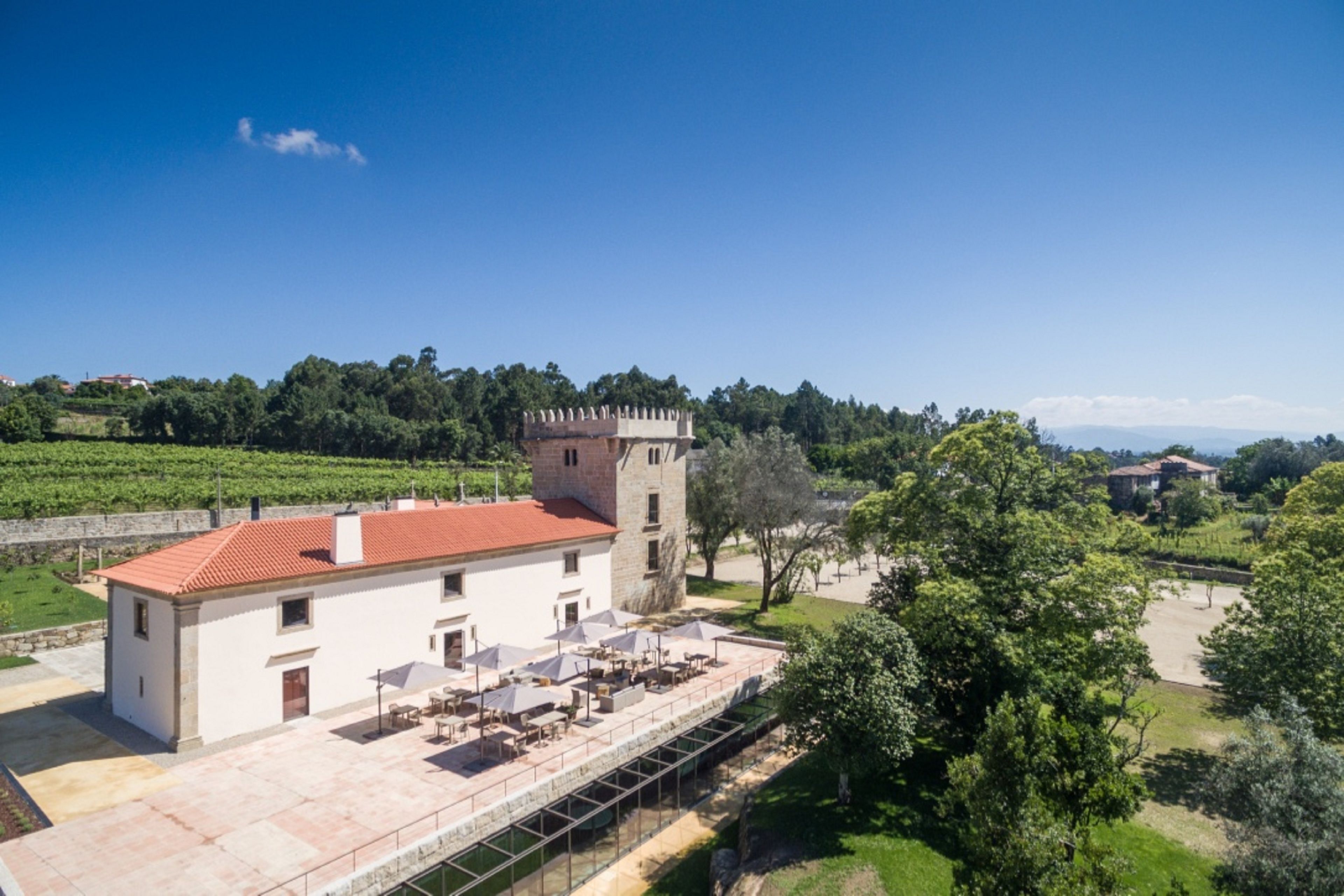 Ein Gebäude mit rotem Ziegeldach, einem Turm und einer Terrasse mit Außenbestuhlung.