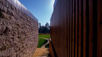 Un sendero que lleva a un edificio con un muro de piedra y una valla de madera.