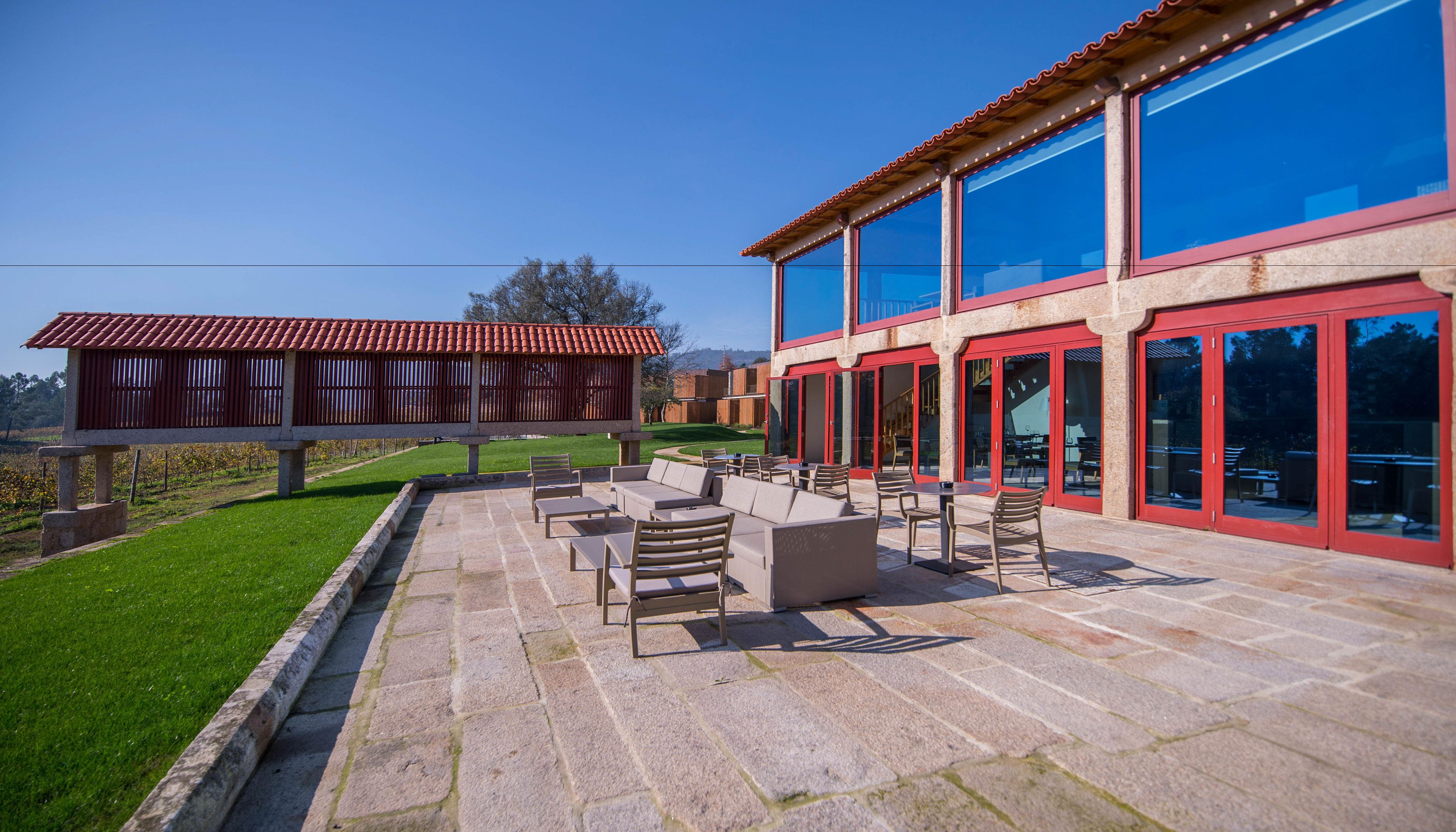 Un patio con mobiliario exterior y vistas a un edificio moderno con amplios ventanales.