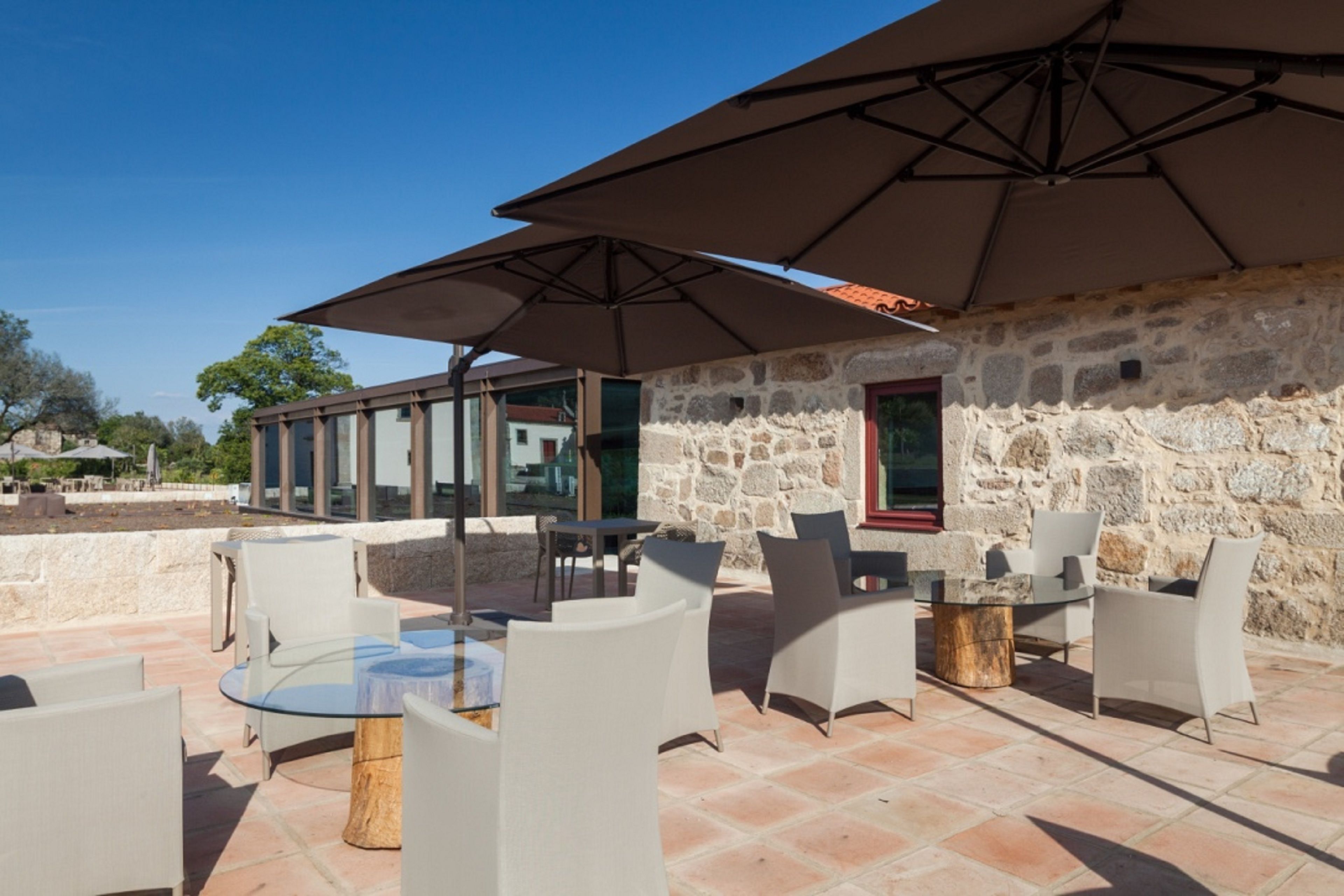 An outdoor patio with stone walls, glass tables, and white chairs.