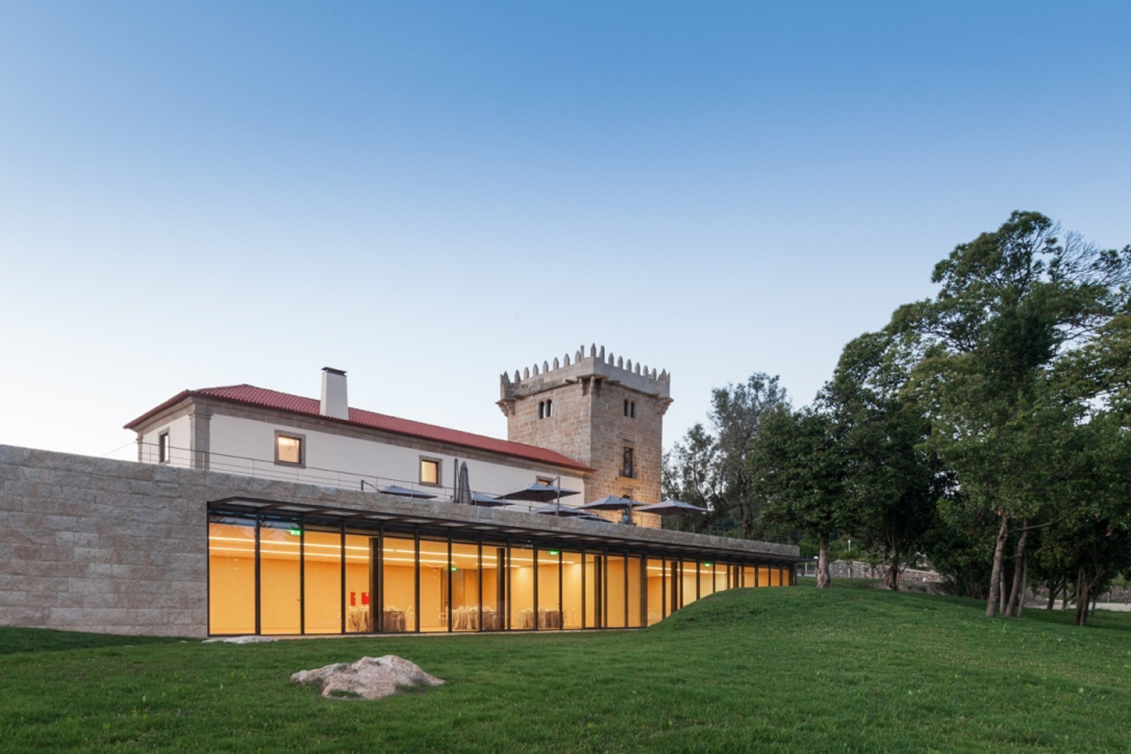 A modern building with a glass facade and a stone tower.