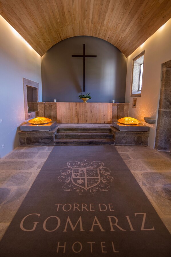 A hotel lobby with a stone floor, a wooden ceiling, and a cross on the wall.