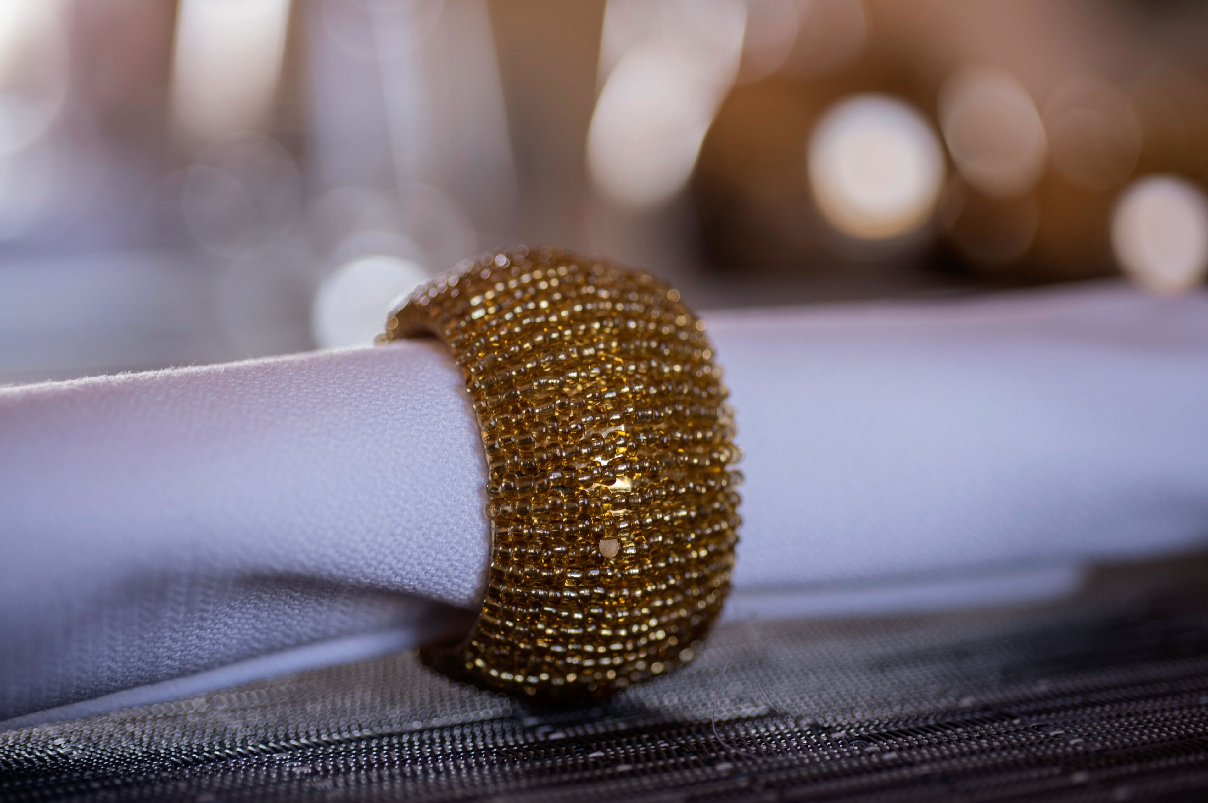 A close-up of a textured fabric with a golden beaded accessory.