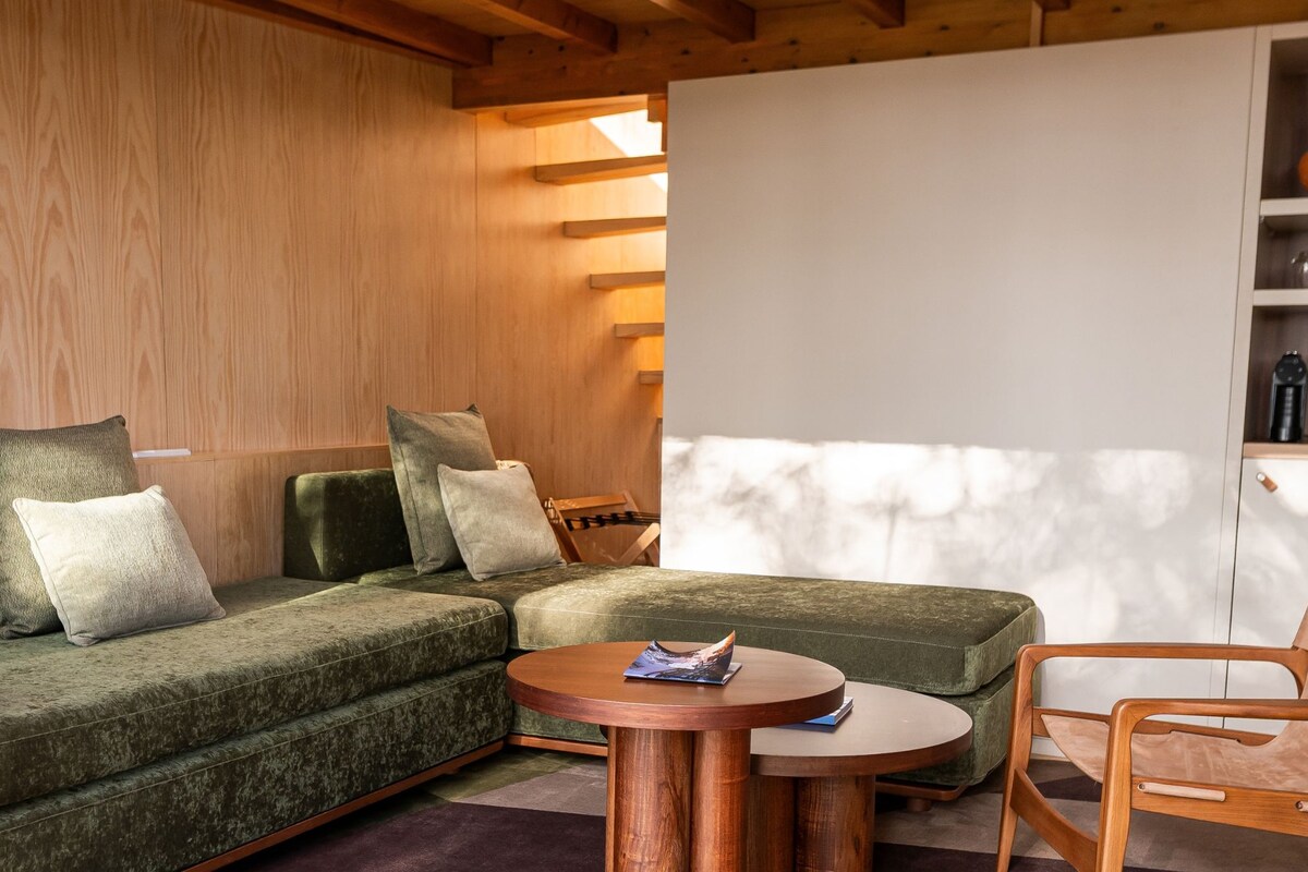 A modern living room with a sectional sofa, two wooden coffee tables, and a wooden chair.