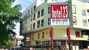 Un hotel de varios pisos con un llamativo letrero rojo que muestra el nombre y el número de contacto.