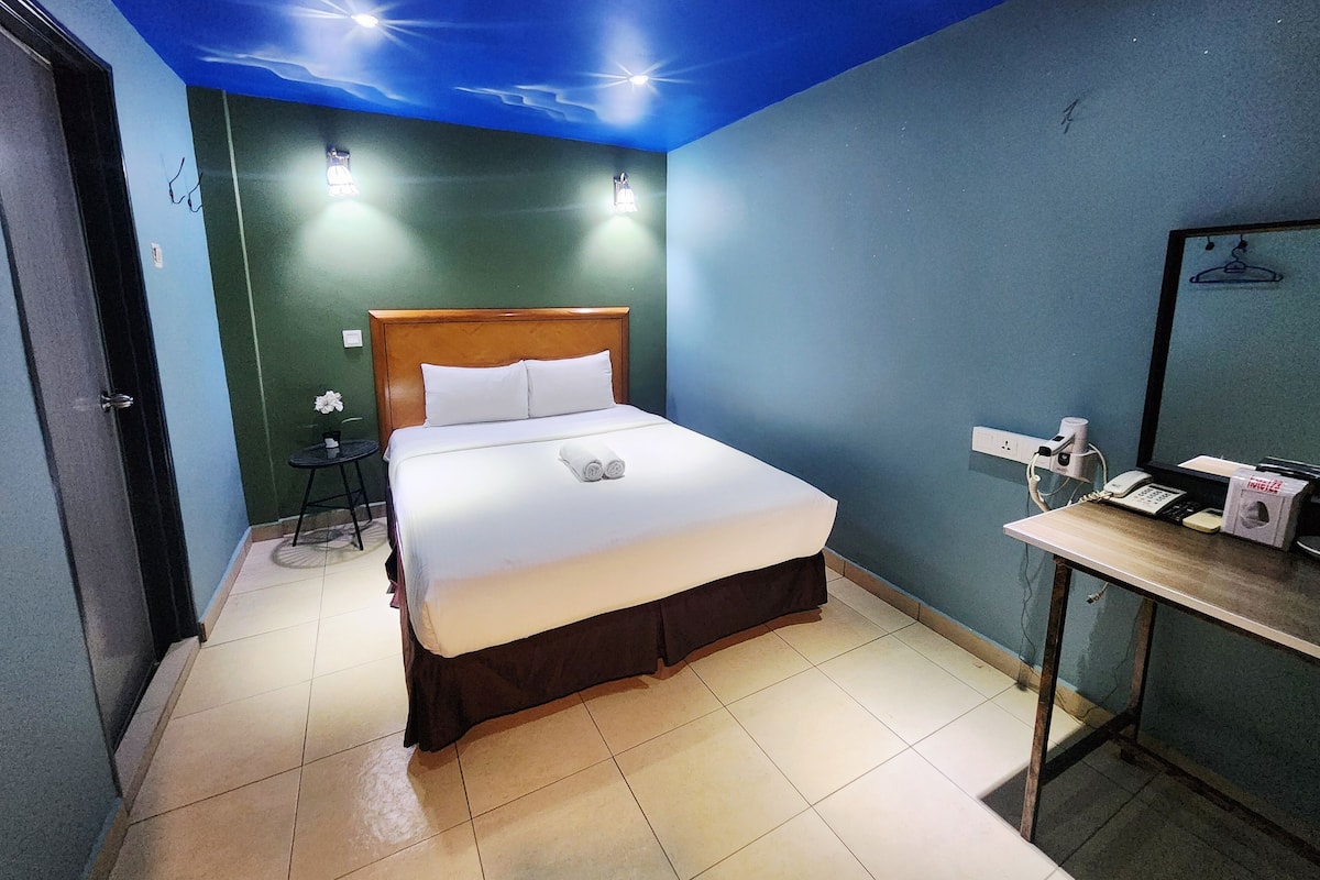 A hotel room with a bed, a desk with a telephone, and a mirror.