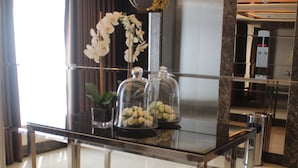 A reception desk with a glass top, a glass dome with flowers, and a small potted plant. - Stradella Hotel (Pasig)