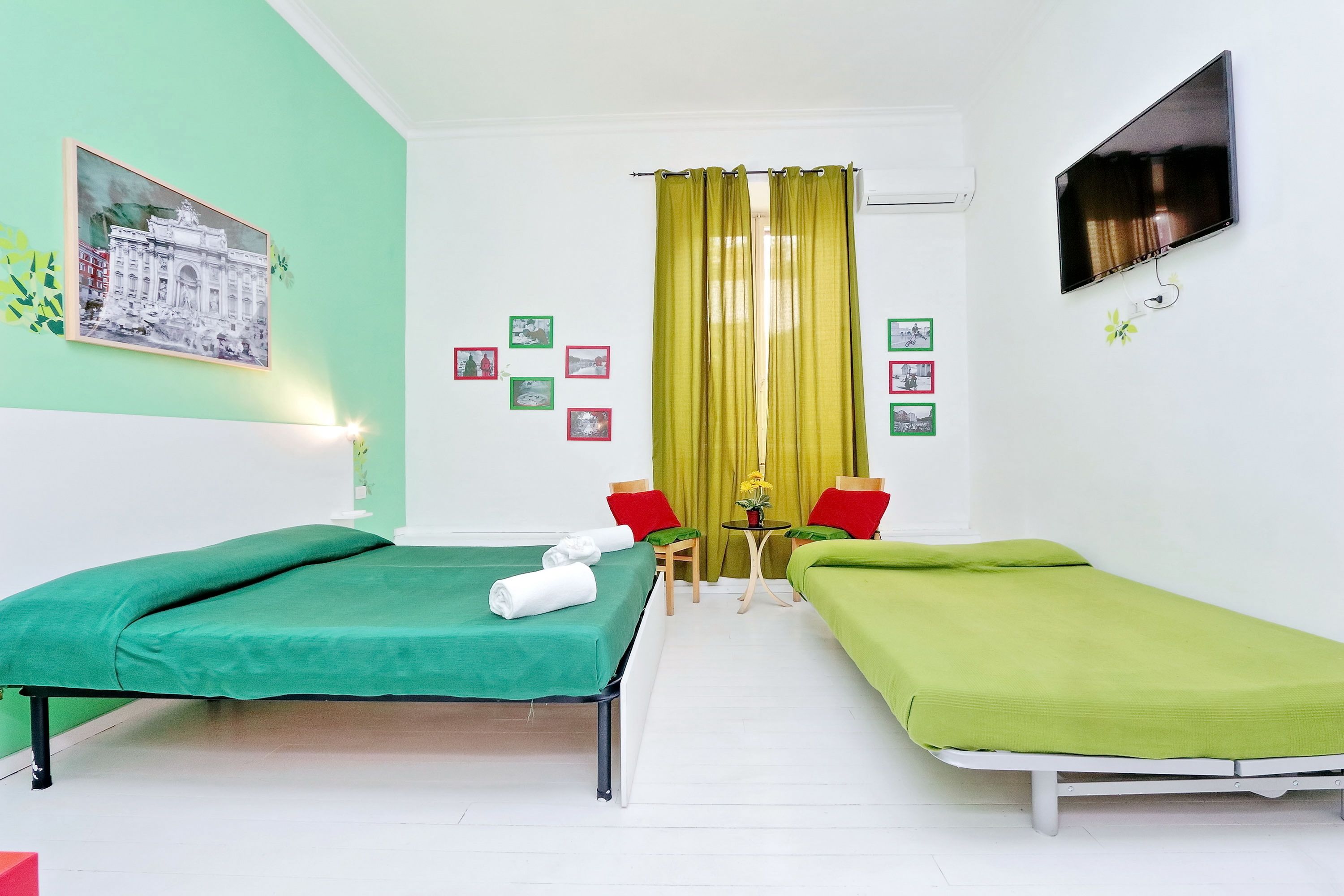 A room with two single beds, a TV, and a painting on the wall.