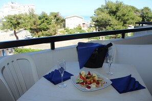 A dining table with a plate of fruit salad, two wine glasses, and a black bucket. - Hotel Cristalda (Vieste)