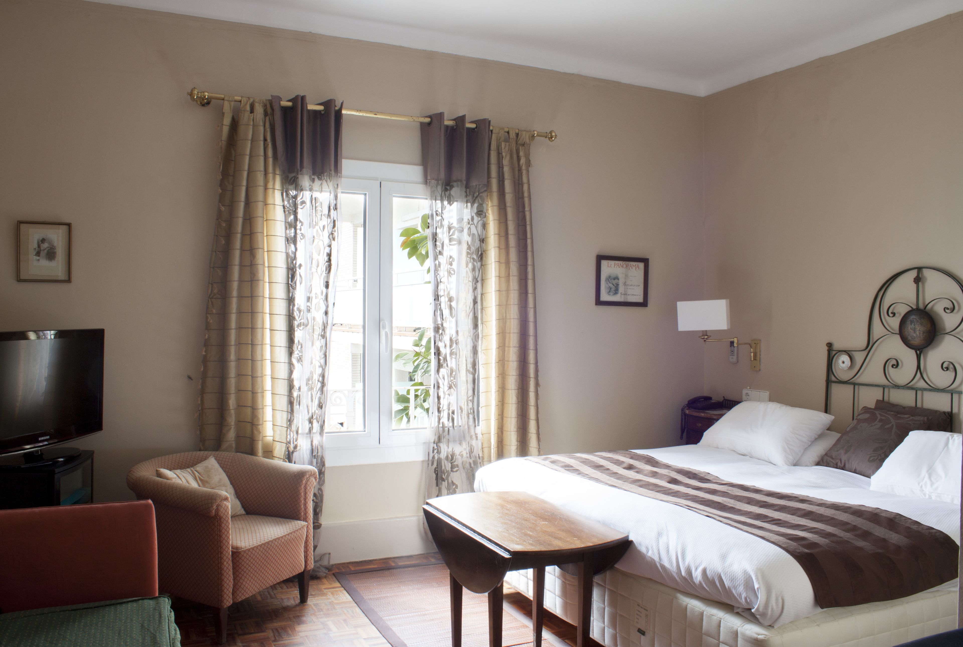 Une chambre à coucher avec un lit, une chaise, une télévision et des rideaux.