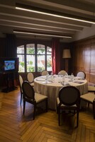 A conference room with a round table, chairs, a television, and a window with curtains.