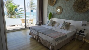 A hotel room with a large bed, a balcony with a view of the sea, and a small table with chairs. - Hotel Subur Maritim (Sitges)