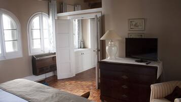 Un dormitorio con cama, cómoda, televisor y ventana con cortinas.