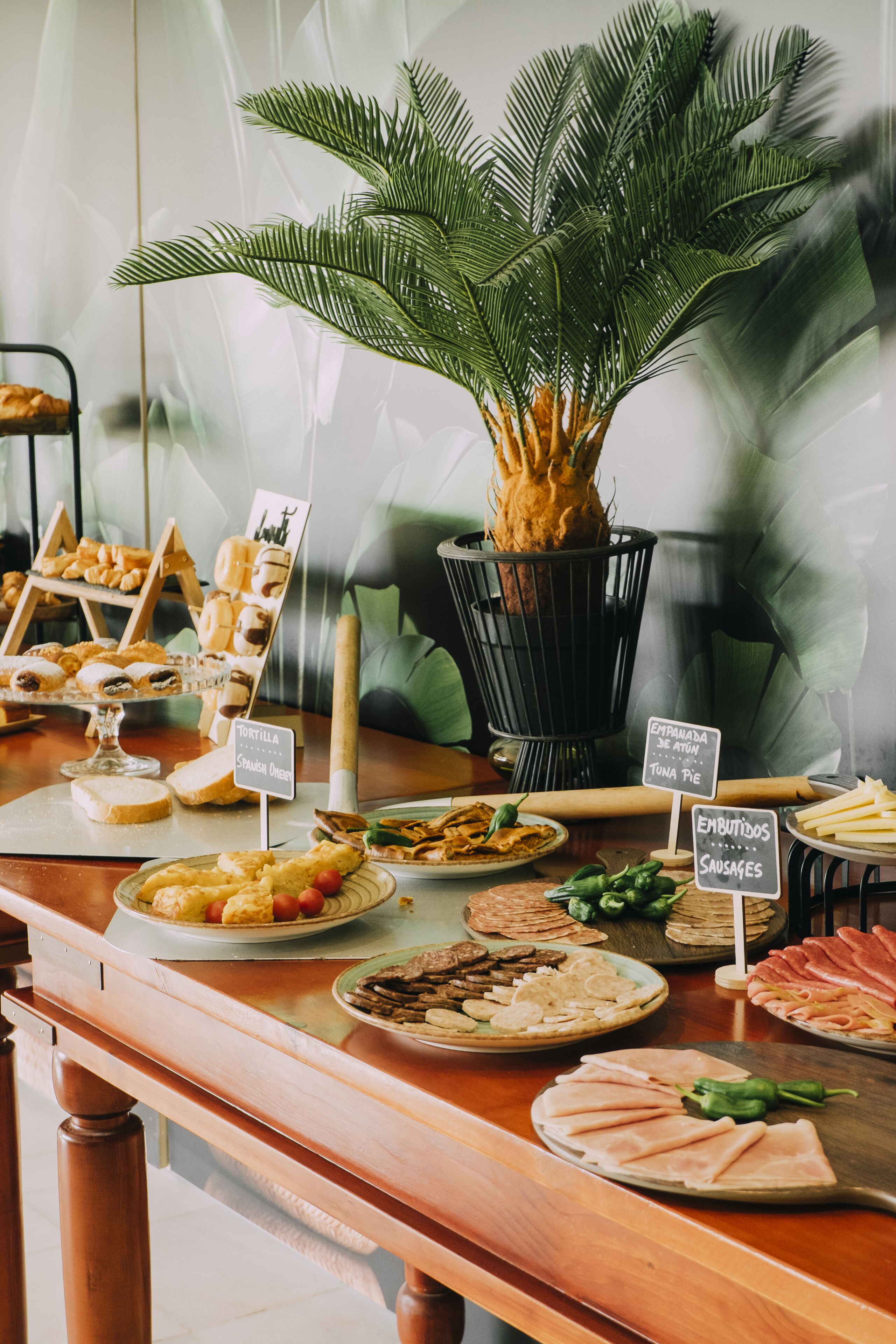 Une table de buffet garnie de divers plats et surmontée d’une grande plante en pot.