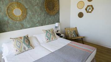 A neatly made bed with patterned pillows, a bedside table with a phone, and decorative wall art.