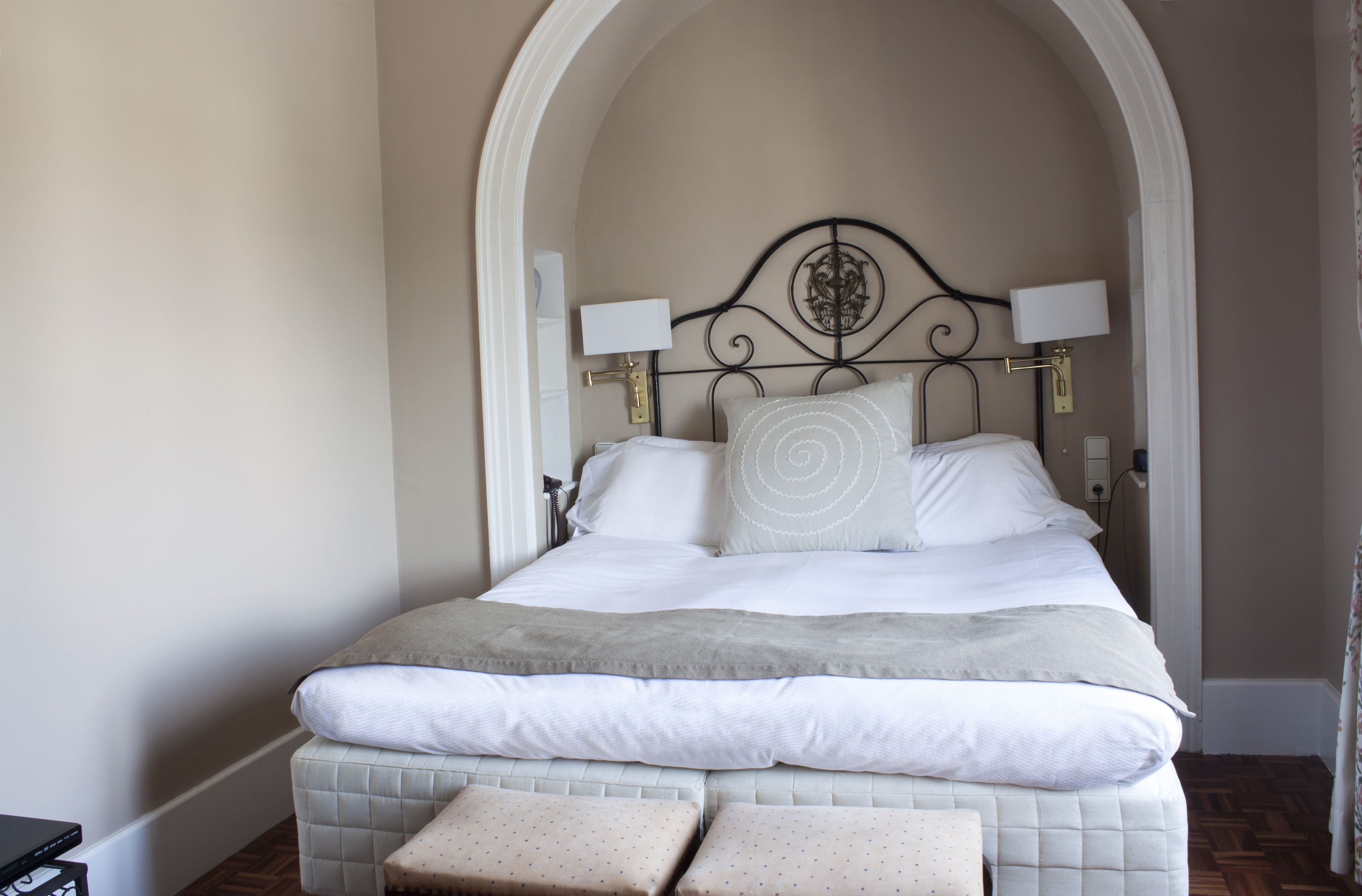 A neatly made bed with a headboard, two bedside lamps, and a decorative pillow.