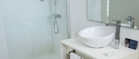 A modern bathroom with a glass-enclosed shower, a white sink, and a large mirror.