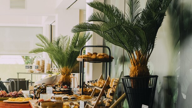 A buffet with various food items and a potted plant. - Hotel Subur Maritim (Sitges)