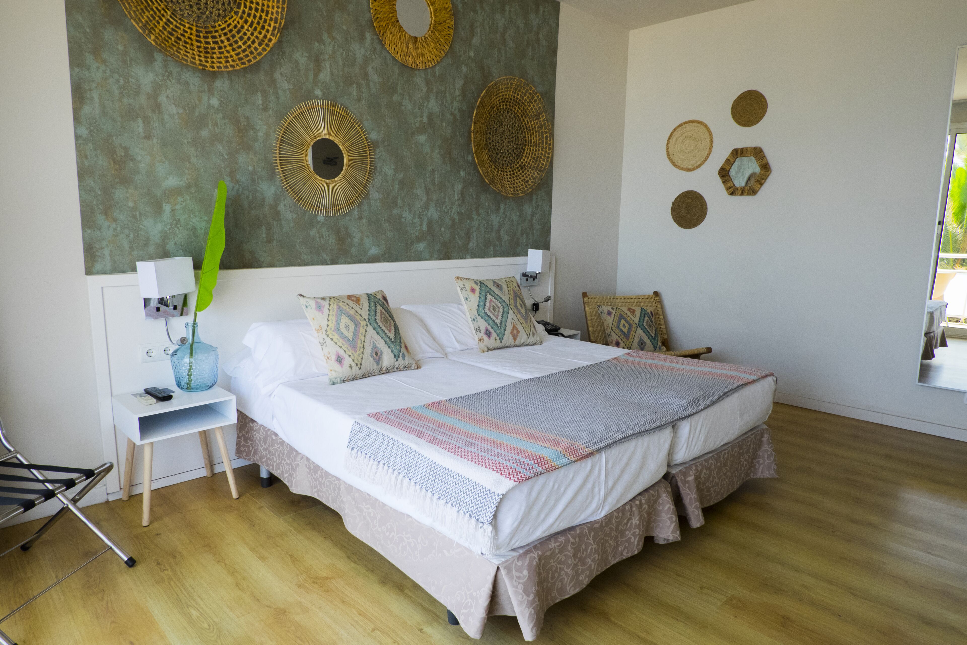 Un letto matrimoniale con cuscini decorati, un comodino con una lampada e decorazioni murali.