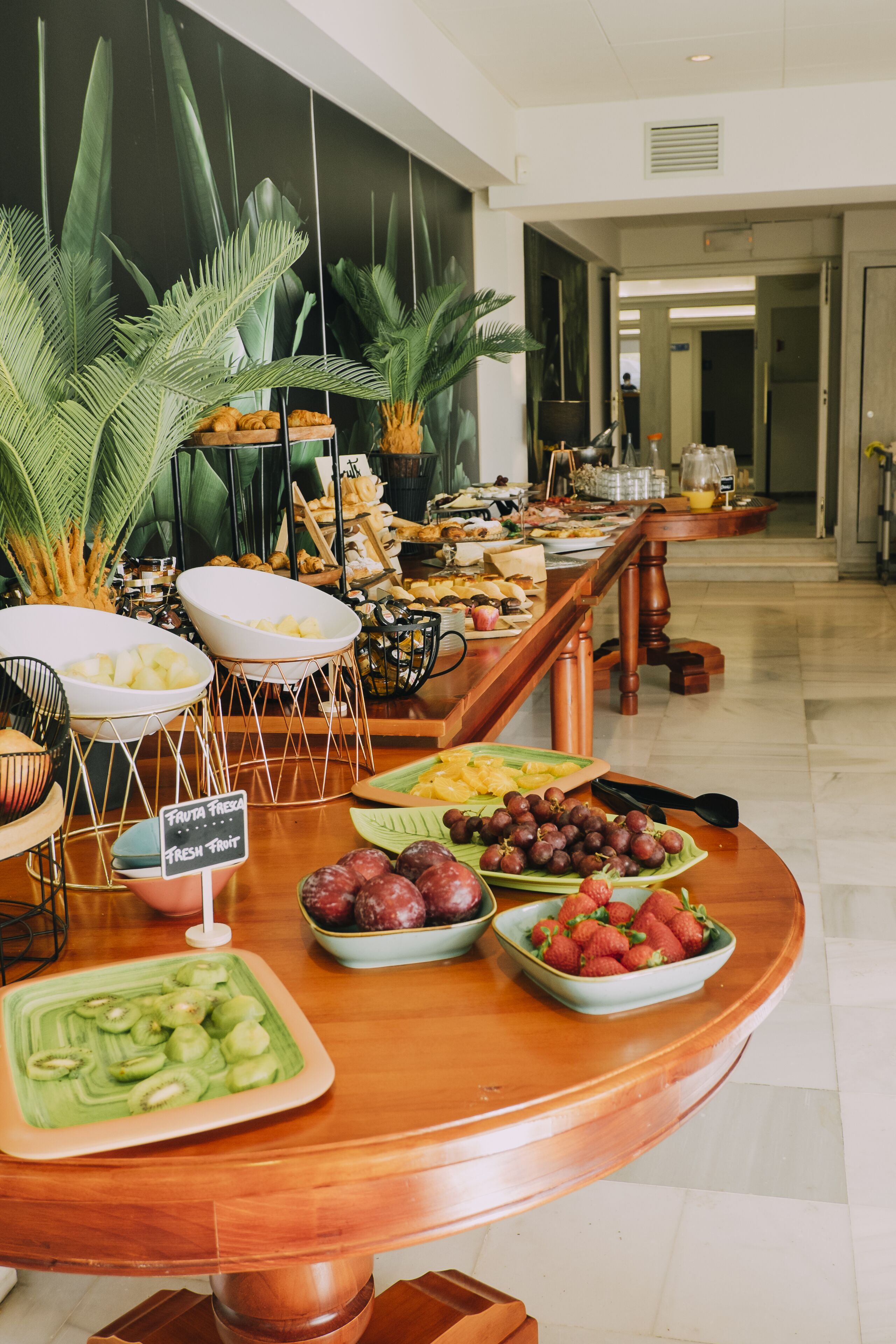 Un buffet proposant une variété de fruits et de légumes, notamment des kiwis, des raisins et des fraises, disposés sur une table en bois.