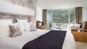 A modern hotel room with a large bed, a sofa, and a balcony with a scenic view. - Hôtel & Spa des Gorges du Verdon (La Palud-sur-Verdon)