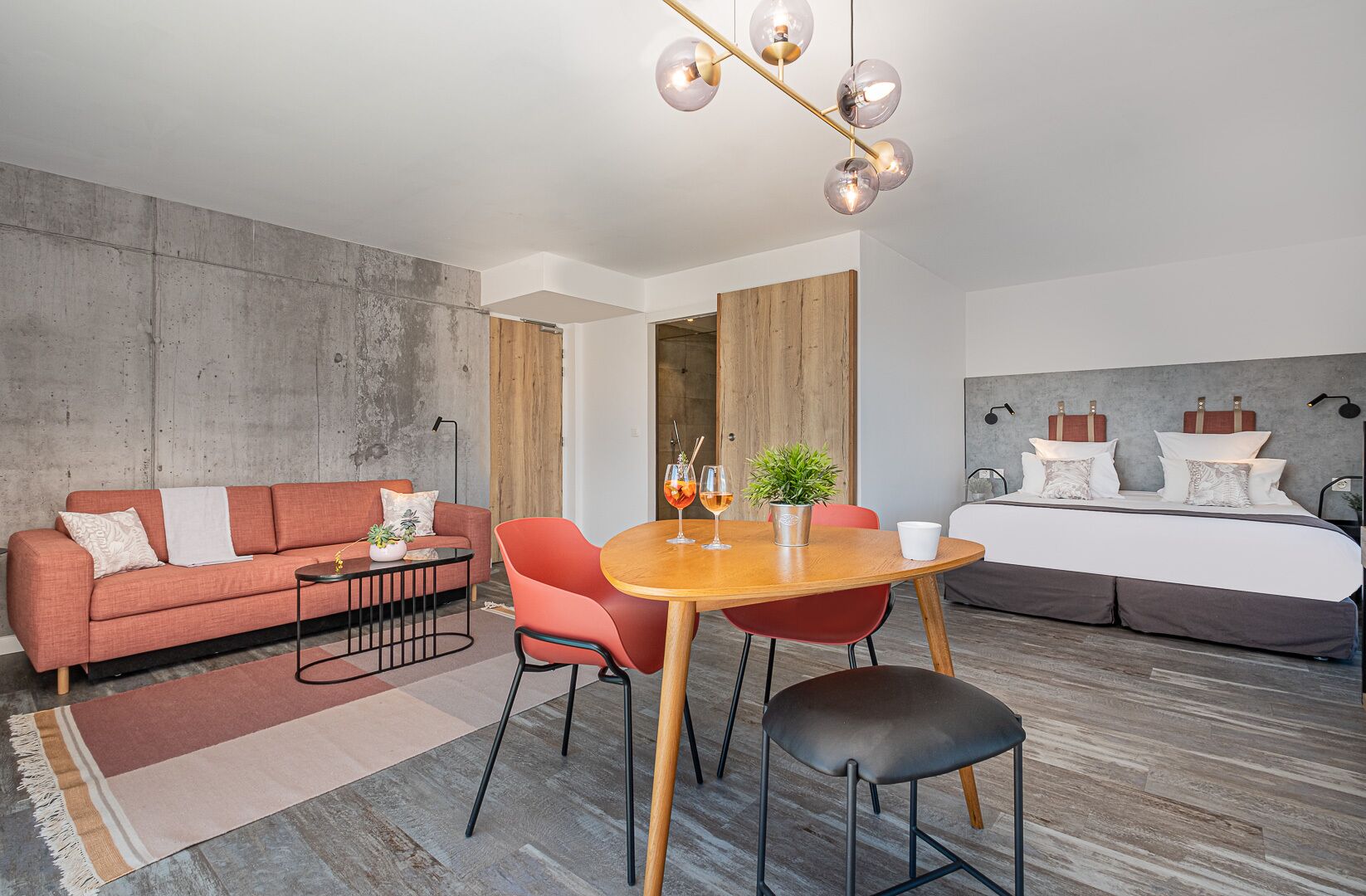 Une chambre d’hôtel moderne équipée d’un canapé, d’une table à manger, de chaises, d’un lit et d’une grande fenêtre.