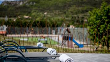Relax in comfort on our outdoor patio, surrounded by lush greenery and a scenic hilly landscape.