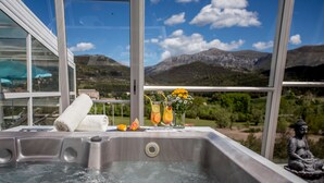 A hot tub with a towel, two drinks, and a flower vase on a balcony with a mountain view. - Hôtel & Spa des Gorges du Verdon (La Palud-sur-Verdon)