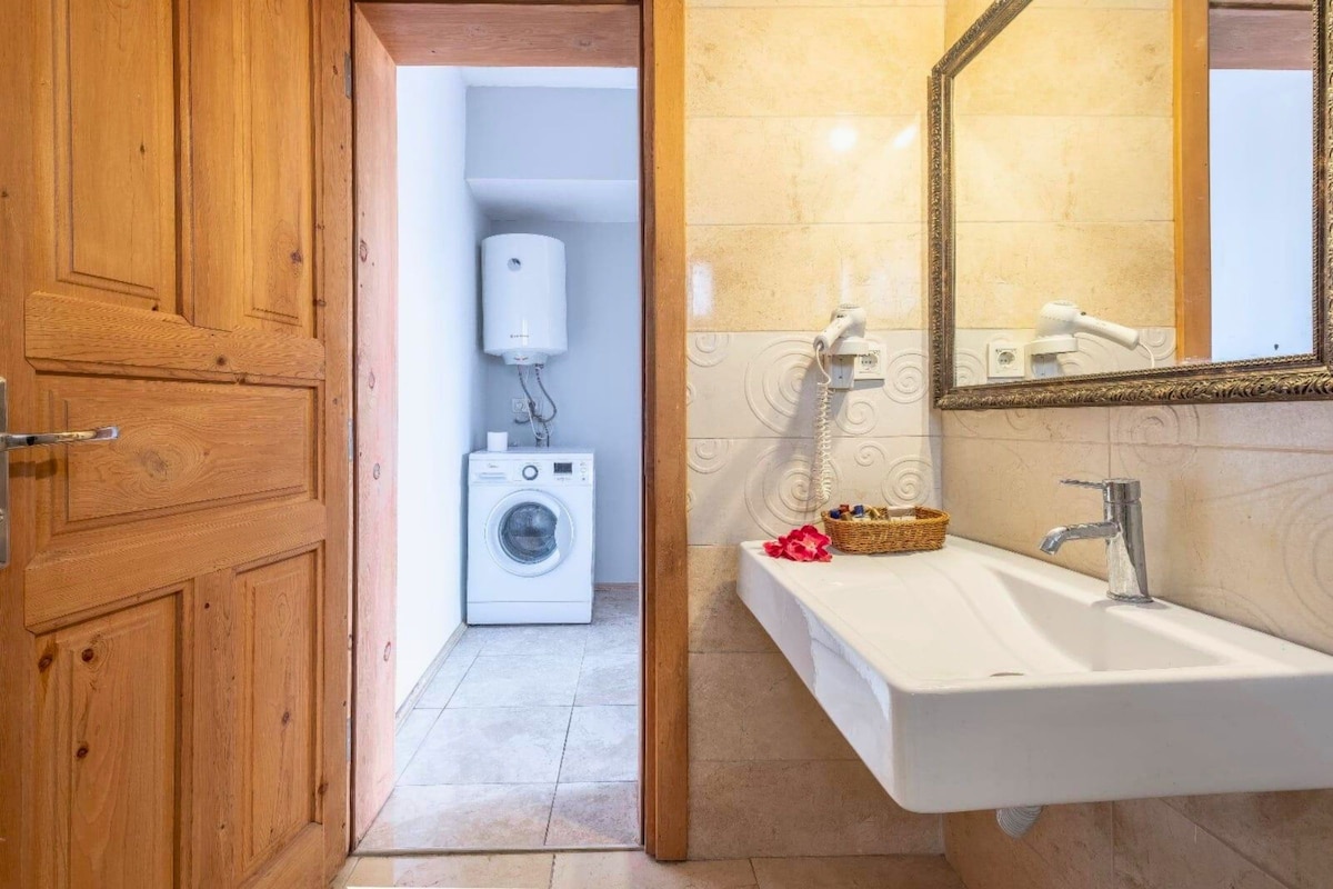 Un baño con lavadora, lavamanos y espejo.