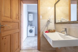 A bathroom with a sink, mirror, and a washing machine in the adjacent room. - Old Town Deluxe Flats (Antalya)