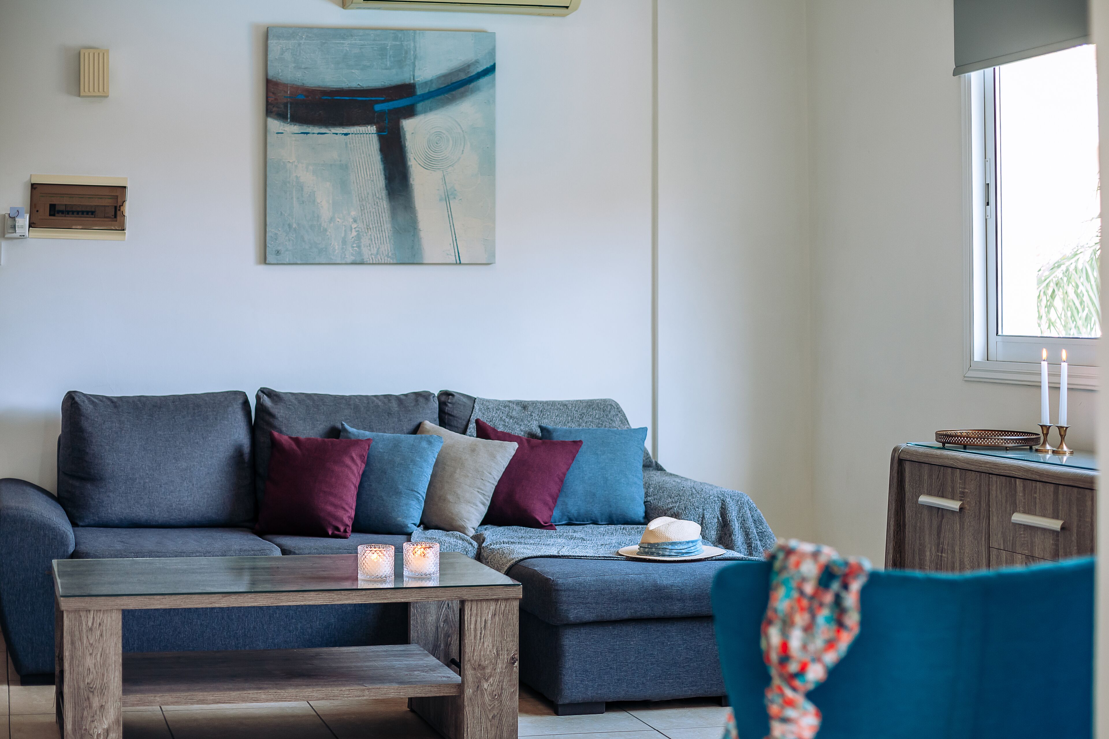 A modern living room with a grey sofa, a wooden coffee table, and a blue armchair.