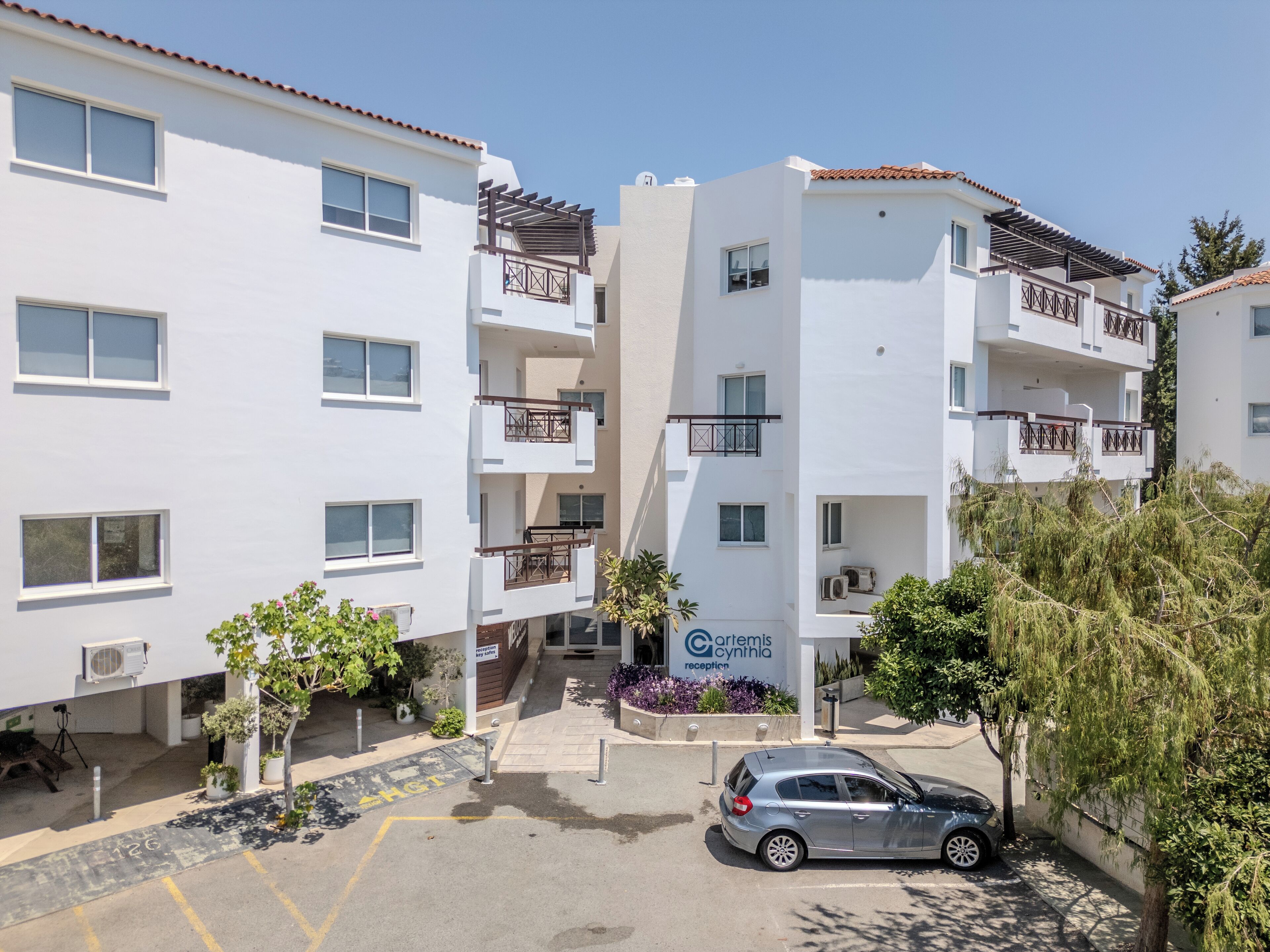 Un hôtel à plusieurs étages doté de balcons, d’un espace de réception et d’un parking.