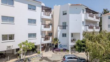 A multi-story hotel with balconies, a reception area, and a parking lot.