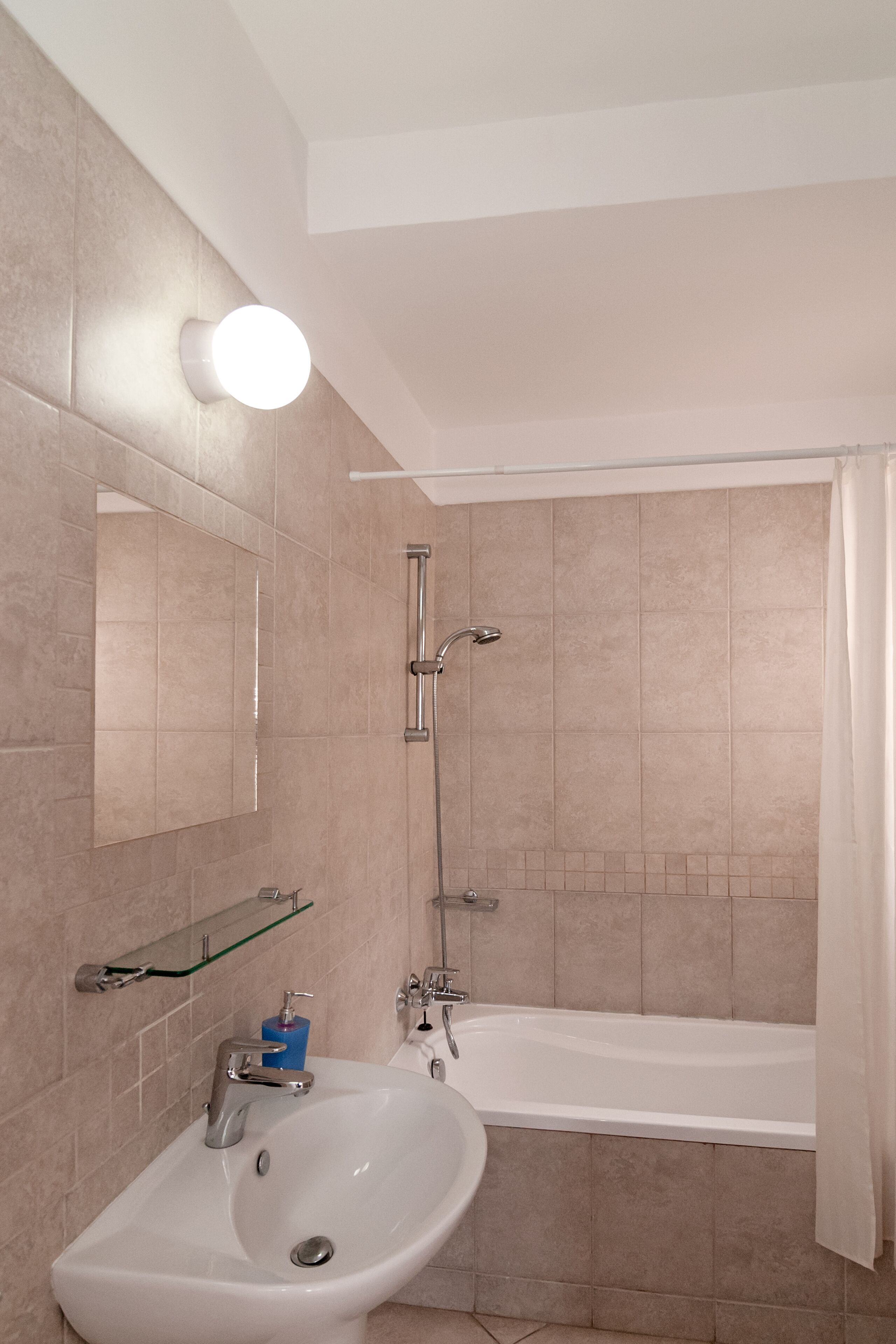 A bathroom with a white sink, mirror, and bathtub.