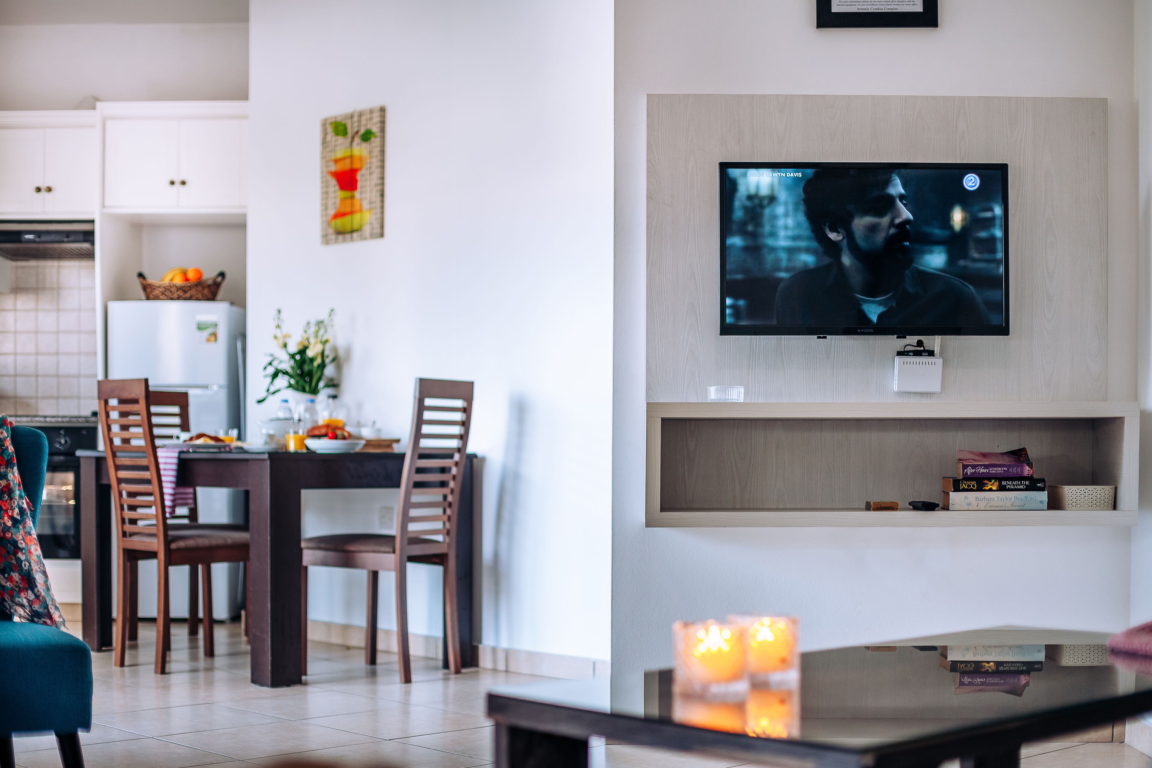 Een moderne woonkamer met een eethoek, een flatscreen televisie aan de muur en een boekenkast.