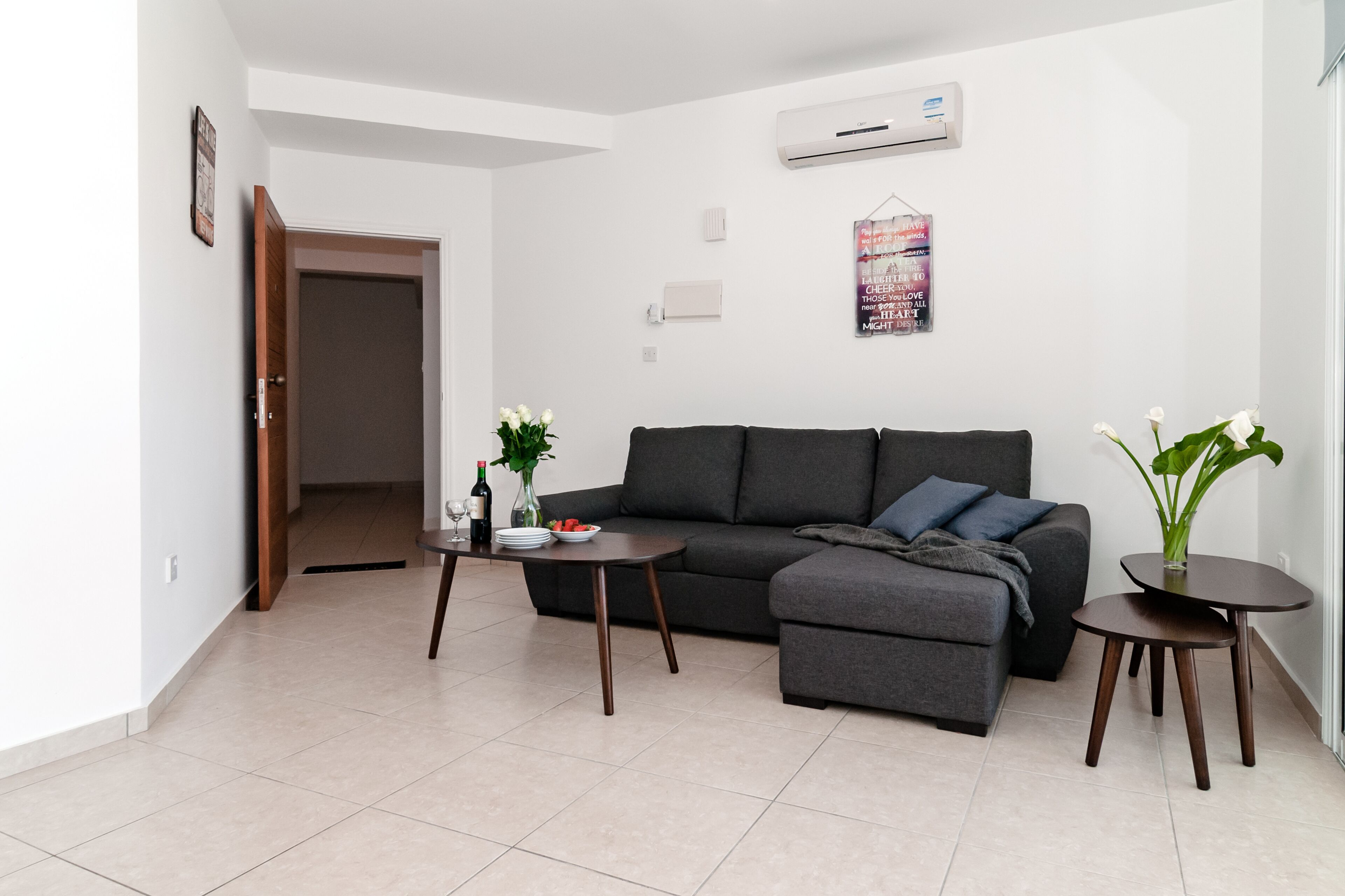 Una sala de estar moderna con un sofá gris, una mesita de centro y una mesita auxiliar con un jarrón de flores.