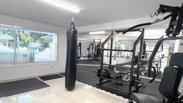 Een sportschool met trainingsapparatuur, een bokszak en grote ramen.