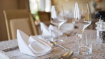 A dining table set with white napkins, silverware, and clear wine glasses.