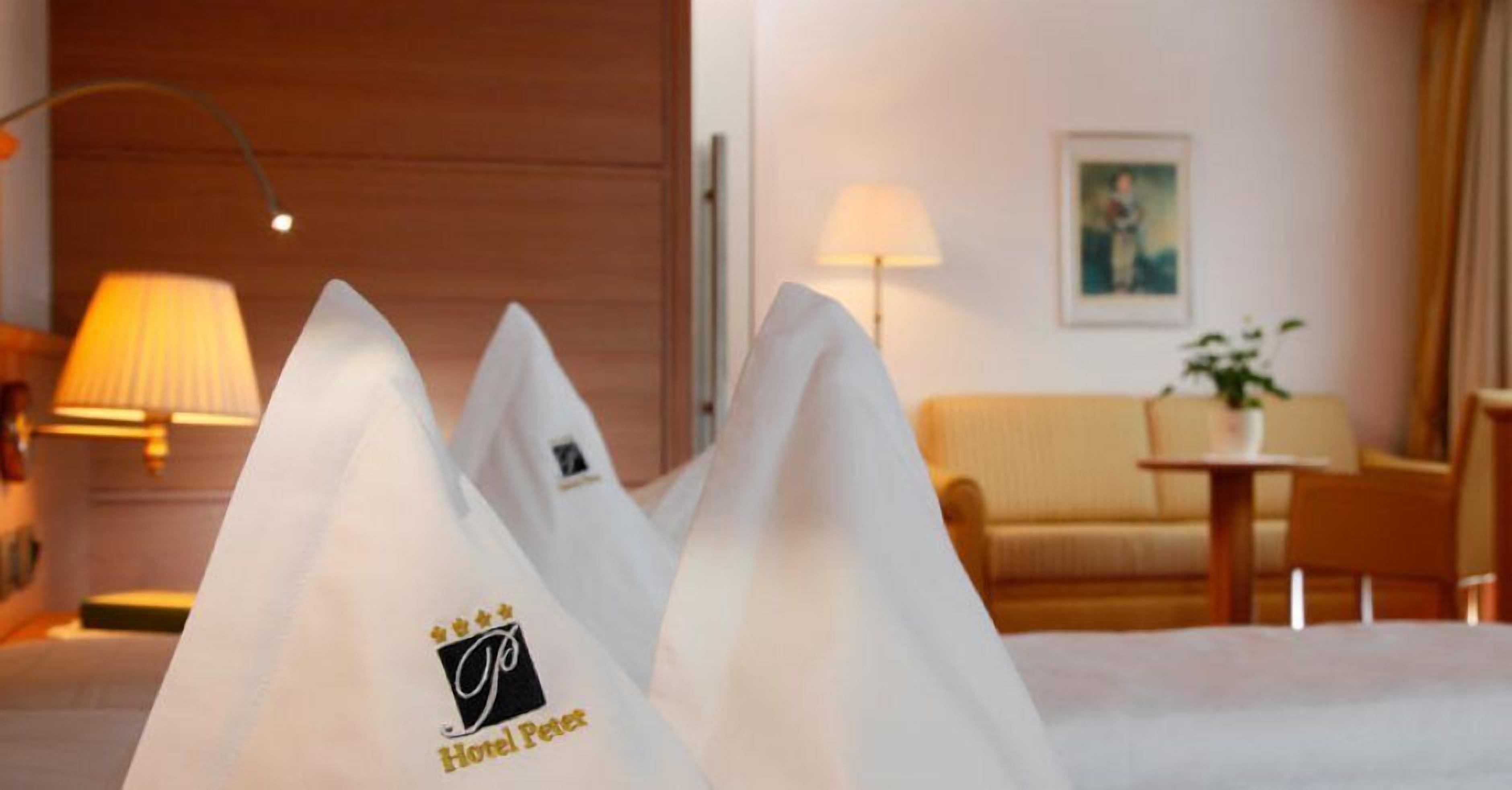 Una camera d'albergo con un letto, due lampade, un divano e un tavolino con una pianta.