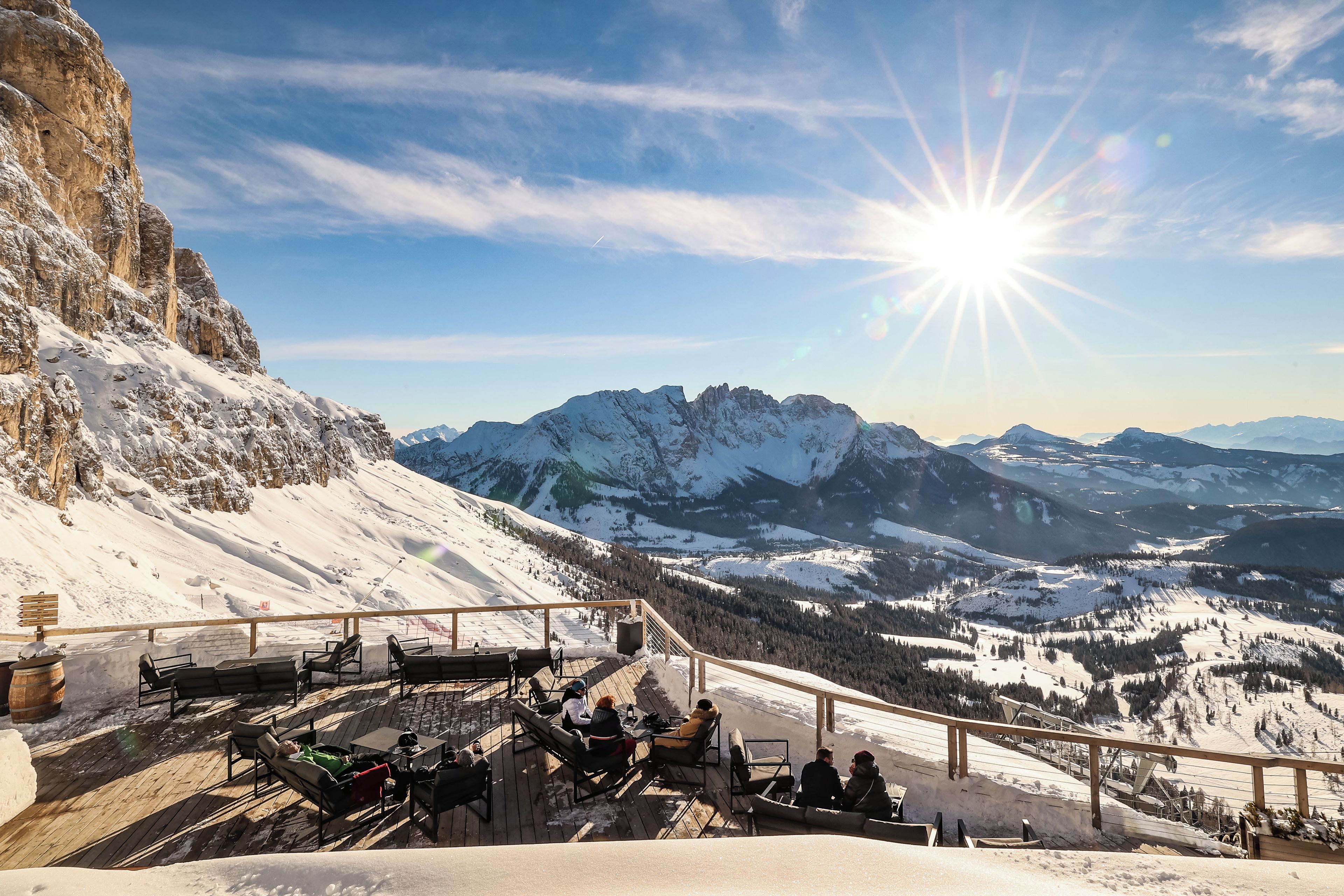 Un paysage de montagne enneigé, avec un soleil brillant dans le ciel.