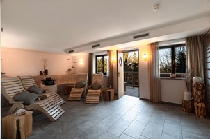 A spacious living area with a fireplace, multiple lounge chairs, and a view of the outdoors.