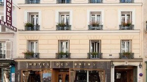 Et hotel med flere etager og balkoner, en bil foran og et skilt med teksten "HOTEL DES BAINS".