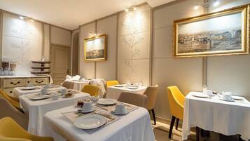 Un comedor con mesas dispuestas para el servicio, una estación de buffet y obras de arte enmarcadas en las paredes.