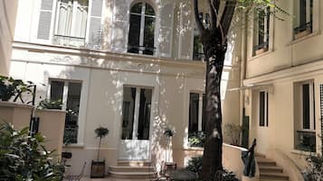 Un patio con un árbol, mobiliario exterior y una escalera.