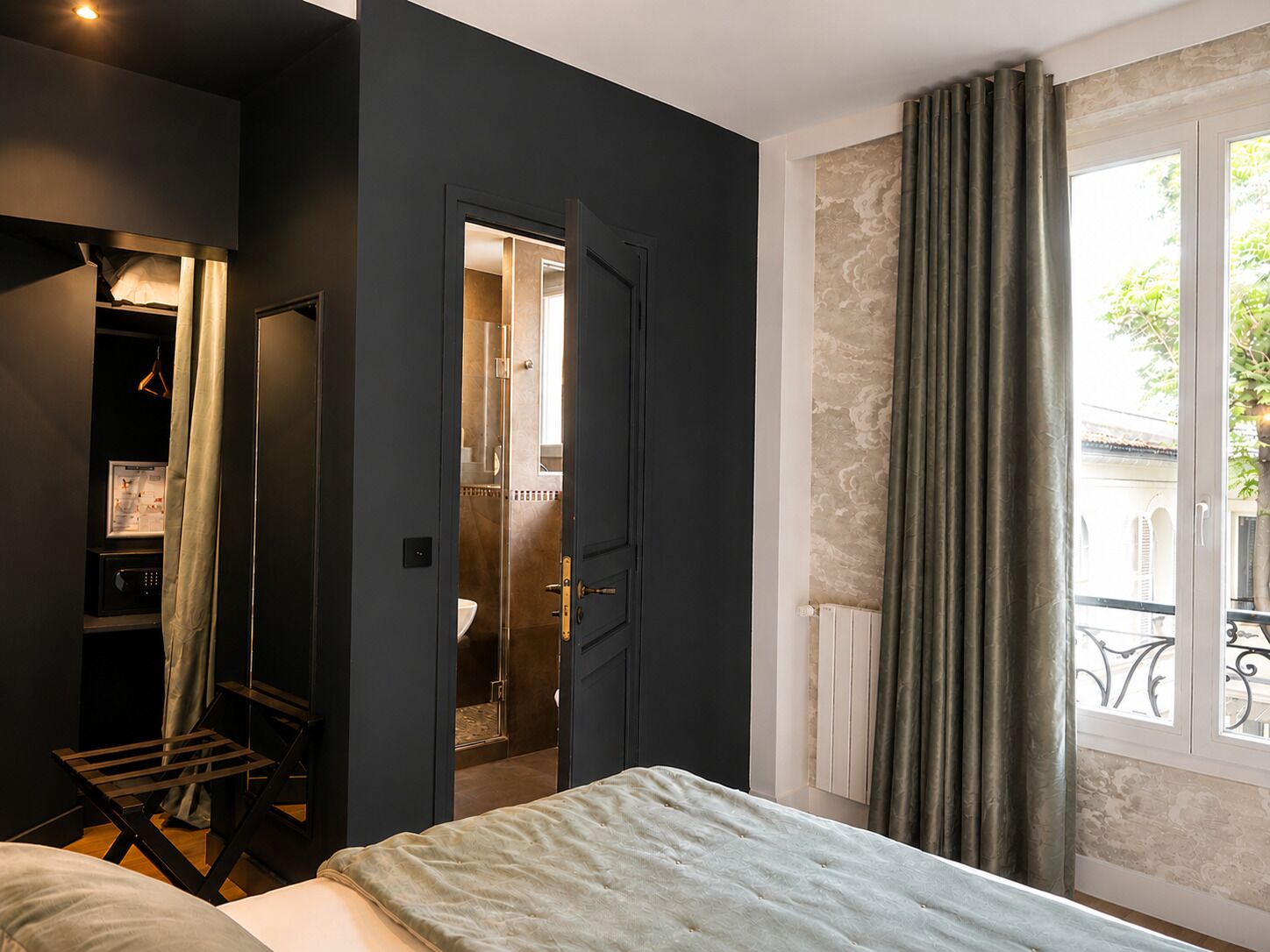 A bedroom with a bed, a wardrobe, a bathroom, and a window with curtains.